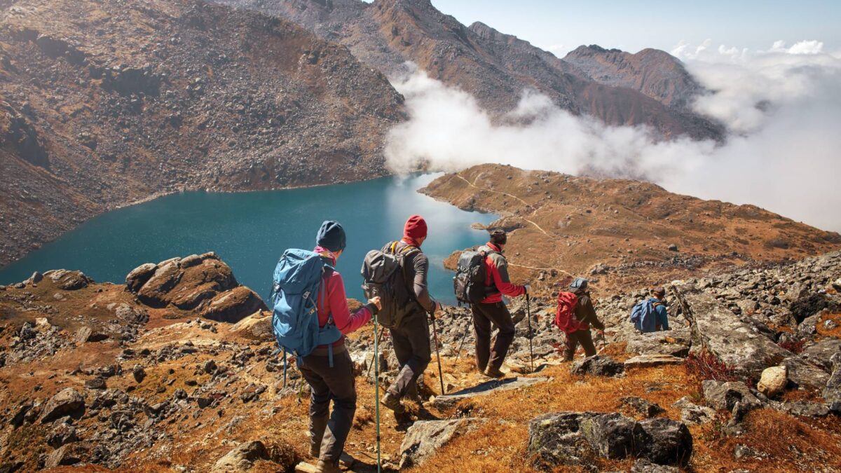 Groep toeristen met rugzakken daalt af bergpad naar het meer tijdens een wandeling in het nationale park Lantang, Nepal. Prachtig inspirerend landschap, trekking en activiteit.