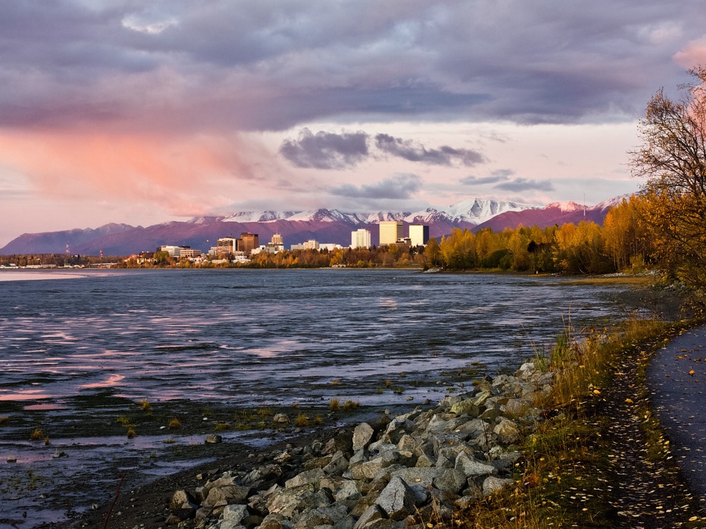 Zicht op de skyline van Anchorage bij zonsondergang vanaf de Tony Knowles Coastal Trail in Alaska – reizen met Explore.