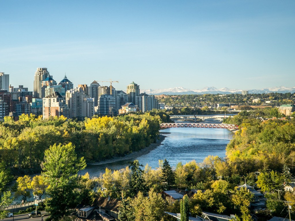 Skyline van Calgary met de Bow River en brug, met de Rocky Mountains op de achtergrond – Canada – reizen met Explore.