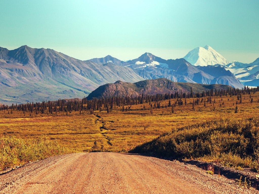 Gravelroad van de Denali Highway met uitzicht op bergen en besneeuwde toppen – reizen met Explore.