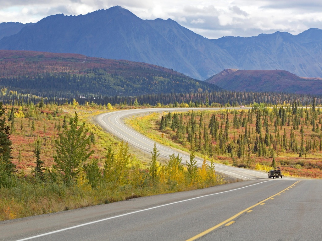 Kronkelende weg door een herfstlandschap met bergen langs de Denali Highway in Alaska – reizen met Explore.