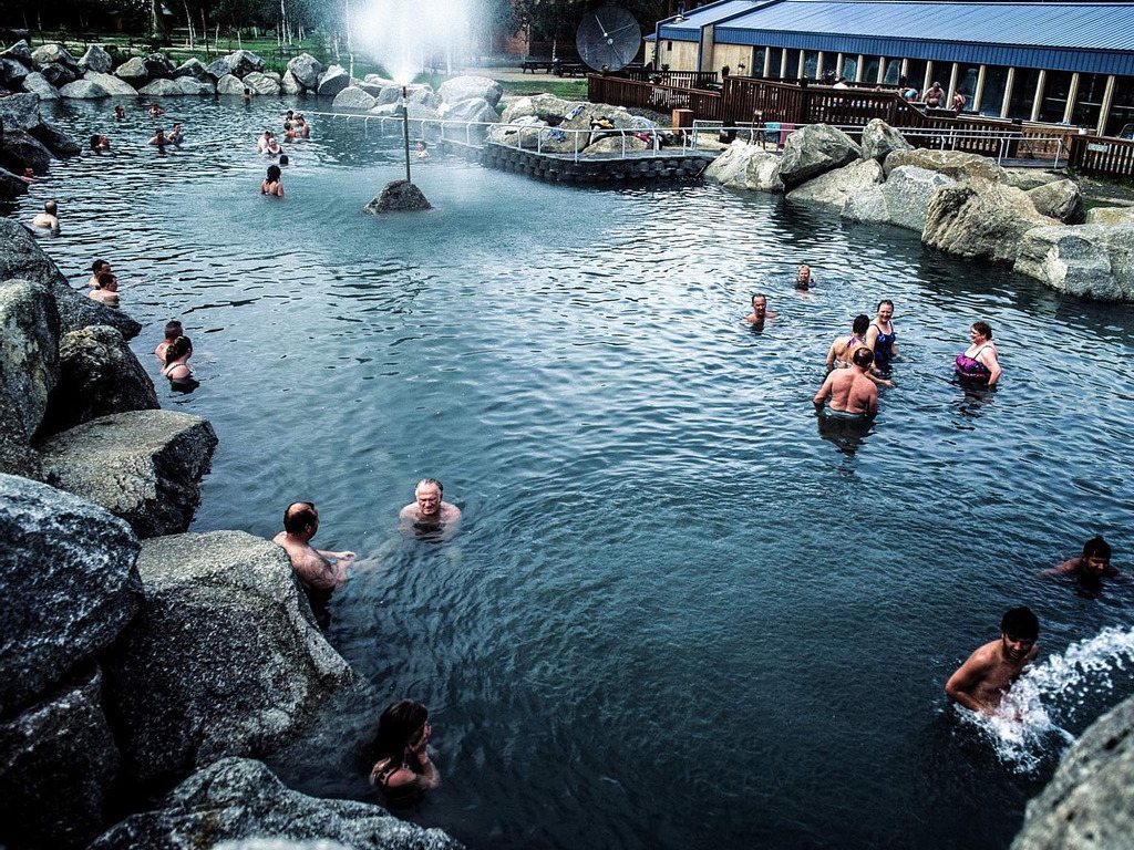 Groep mensen in natuurlijke warmwaterbron bij Chena Hot Springs, Alaska – reizen met Explore.