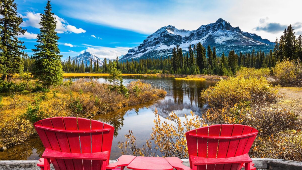 Twee rode stoelen met uitzicht op besneeuwde bergen langs de Icefields Parkway in Canada – reizen met Explore