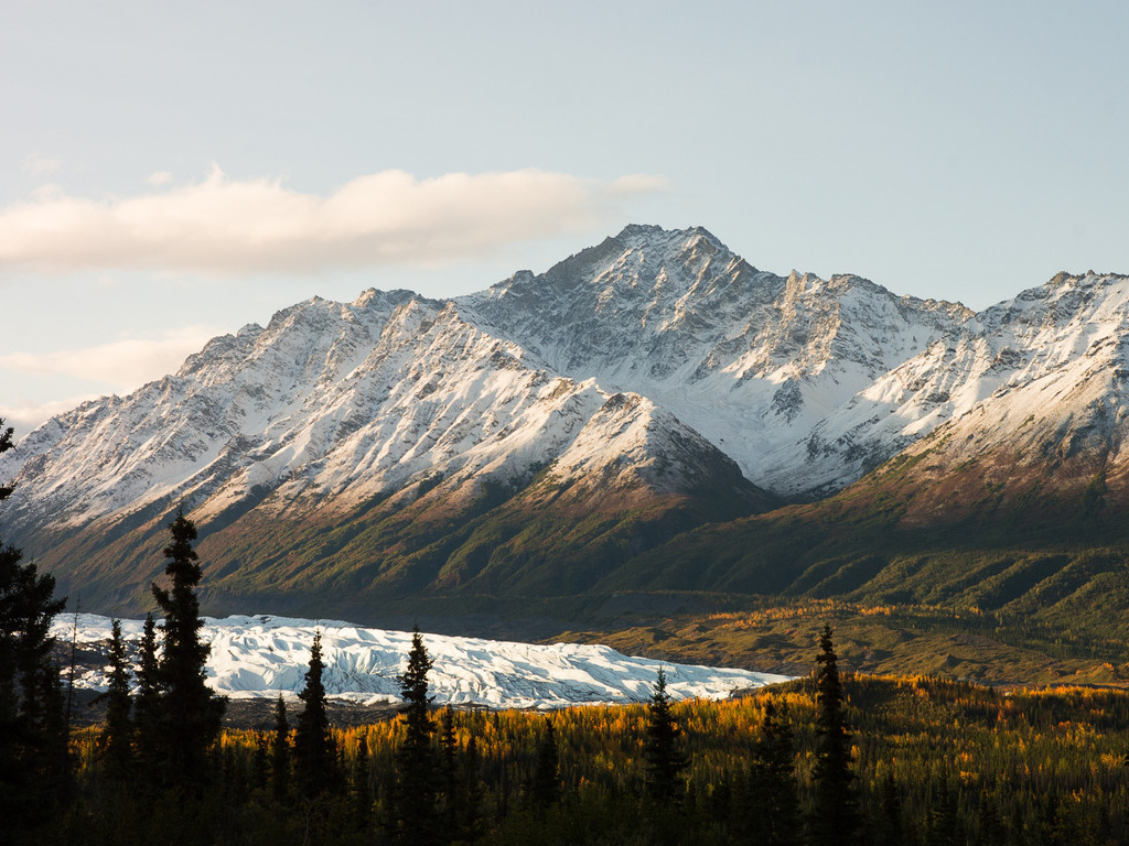 Uitzicht op de Matanuska-gletsjer met besneeuwde bergtoppen en herfstkleurig woud in Alaska – reizen met Explore.