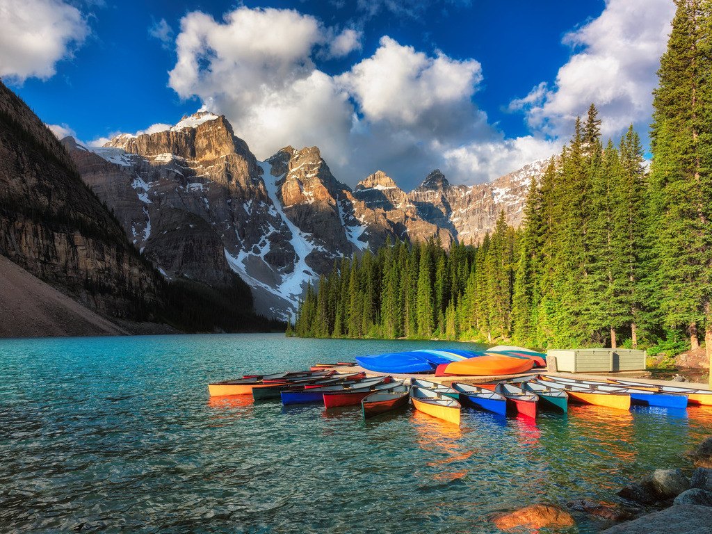 Kano’s op het turquoise water van Moraine Lake omgeven door hoge bergen en groene bossen – Canada – reizen met Explore.