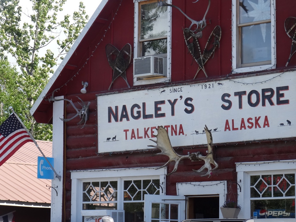 Rood houten gebouw met witte gevel van Nagley’s Store in Talkeetna, Alaska, versierd met geweien – reizen met Explore.