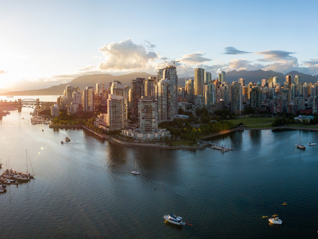 Een rotsachtige kustlijn met uitzicht op een iconische rotspunt en beboste kliffen bij Vancouver Island, Canada. De avondzon werpt een warme gloed over het landschap – reizen met Explore.