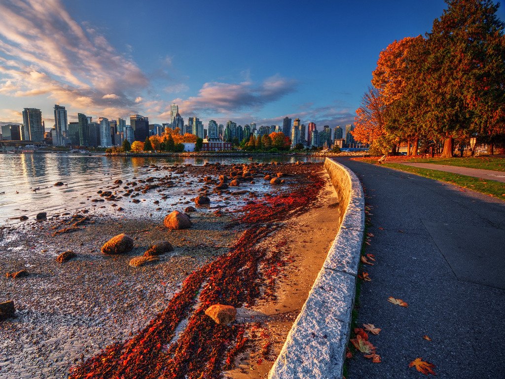 Uitzicht op de skyline van Vancouver vanuit Stanley Park, met herfstkleuren en een gouden gloed bij zonsondergang – reizen met Explore