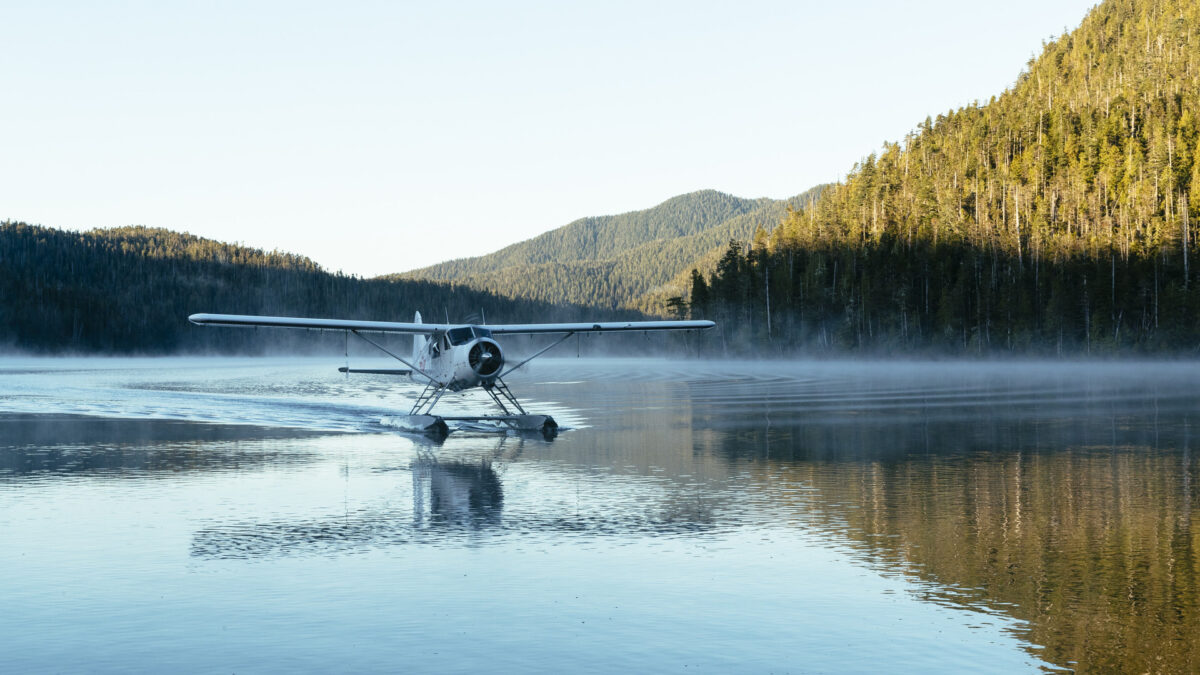 Watervliegtuig op een spiegelglad meer omringd door bossen op Vancouver Island, Canada – reizen met Explore