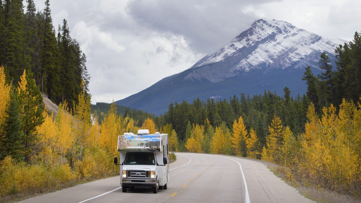 Motorhome rijdt op weg met berglandschap en besneeuwde toppen in Banff National Park, Canada – reizen met Explore.