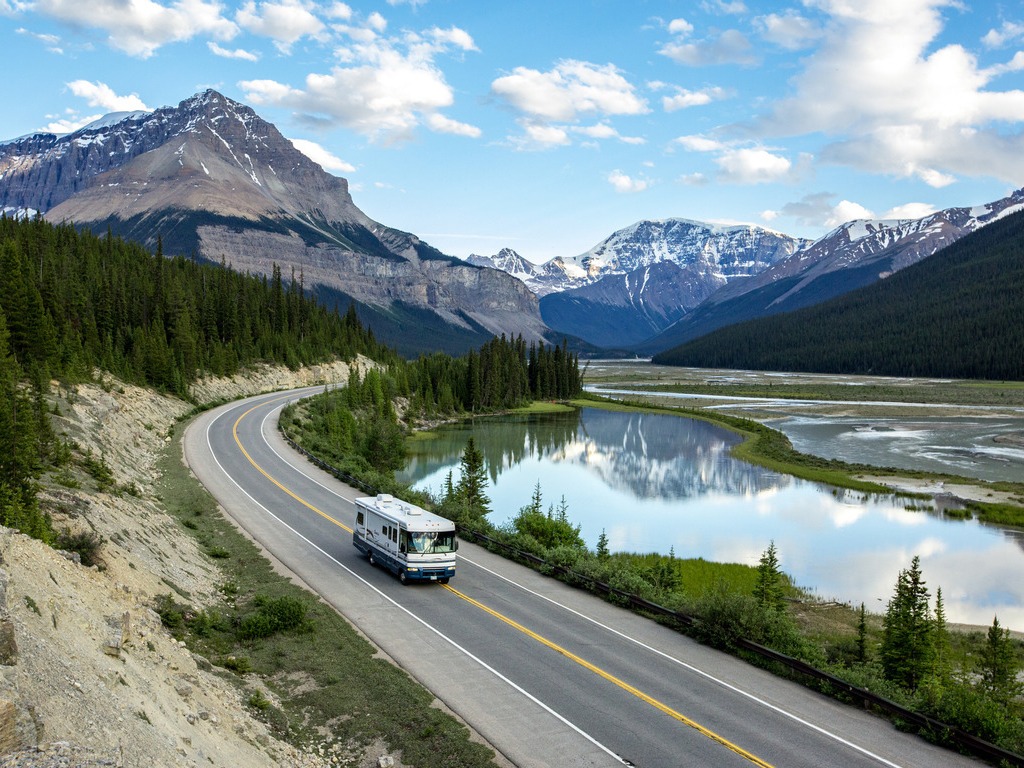 Motorhome rijdt langs Icefields Parkway met bergen en rivier in Jasper National Park, Alberta, Canada – reizen met Explore.