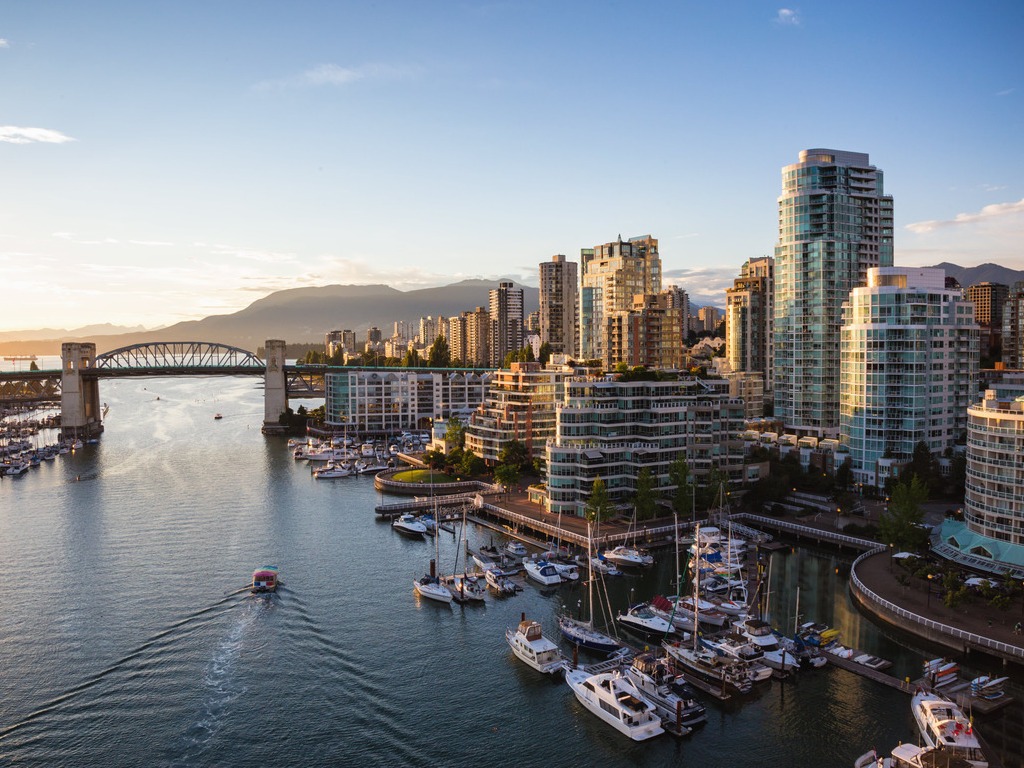 SkyTrain op een moderne brug met witte tuikabels, met op de achtergrond wolkenkrabbers en de bergen bij Richmond Centre – Canada – reizen met Explore.