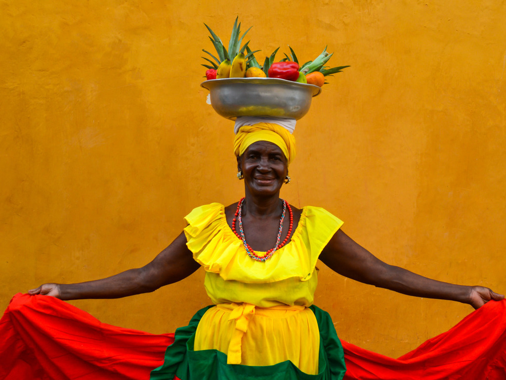 Vrouw in traditionele kleding met fruitmand op hoofd in Cartagena, Colombia – reizen met Explore.