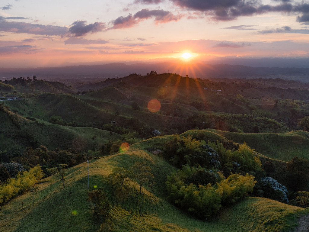 Zonsondergang boven glooiende groene heuvels in de koffiezone bij Salento, Colombia – reizen met Explore.