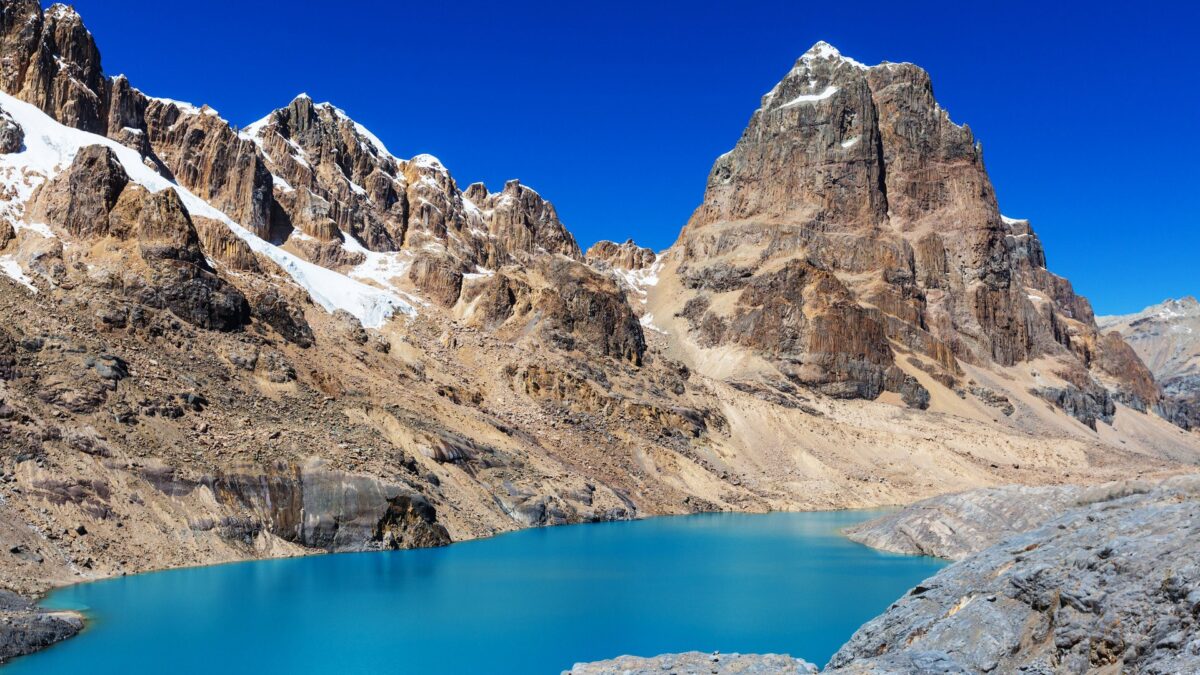 Turquoise bergmeer omgeven door rotsachtige bergen met sneeuw, Andes, Peru – reizen met Explore.