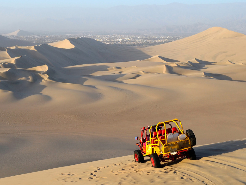 Buggy rijdt over zandduinen bij Huacachina, Ica regio, Peru – reizen met Explore.