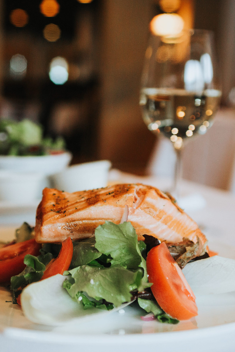 Restaurant met zalm op de eettafel samen met een glaasje wijn - reizen met Explore