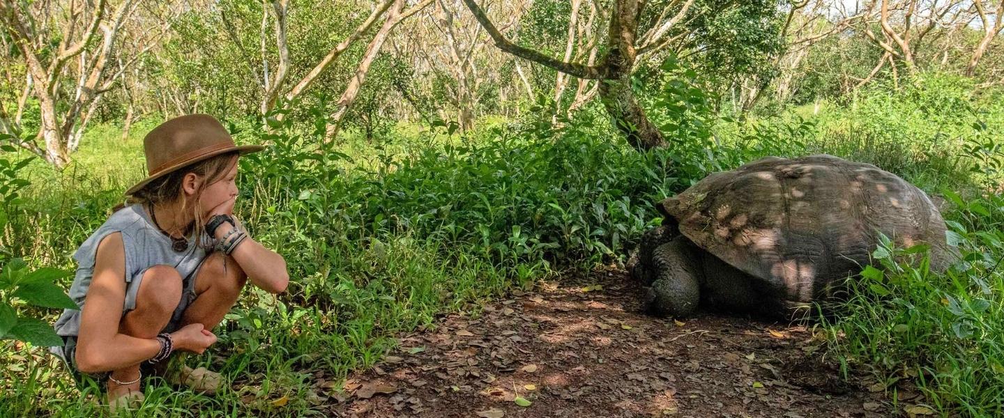 Meisje kijkt naar schildpad op Galapagos - reizen met Explore